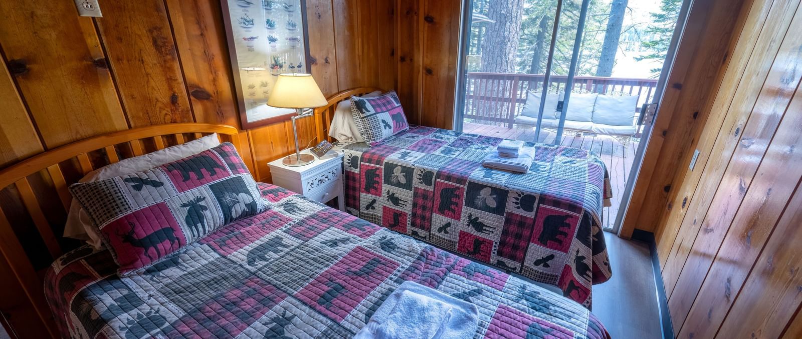Twin beds with patchwork bedding and forest views at Kit Carson Lodge.