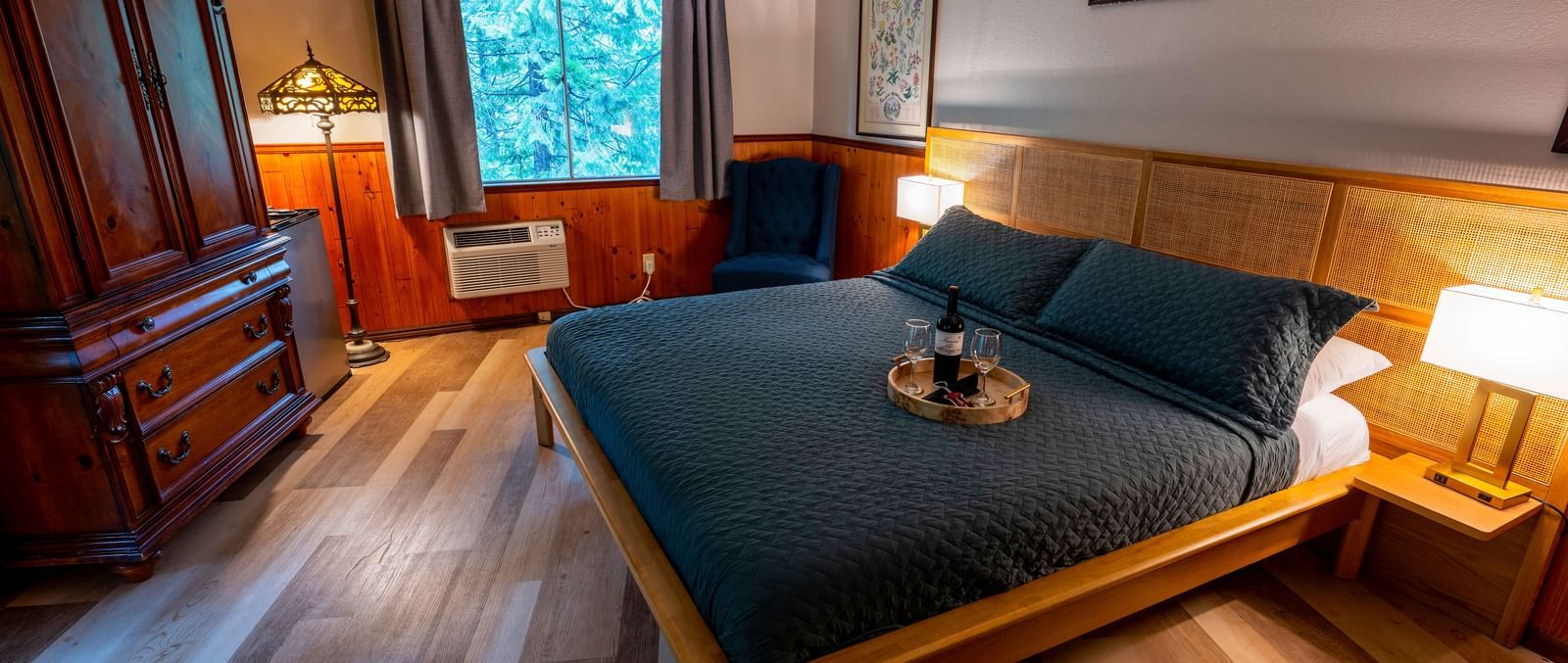 Cozy guest room at Narrow Gauge Inn featuring dark blue bedding, wooden furniture, and warm lighting.