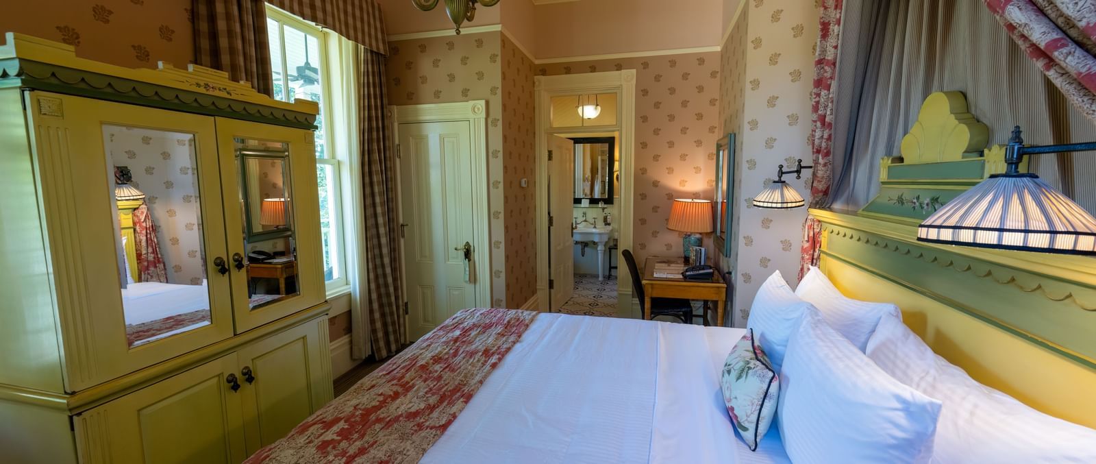 A luxurious bedroom featuring a large, inviting bed with crisp white linens and elegant wallpaper at The Tallman Hotel.