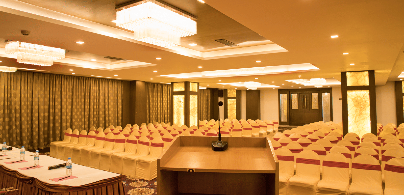 A conference room at Benzz Park Chennai set up with rows of tables and chairs, facing a podium.