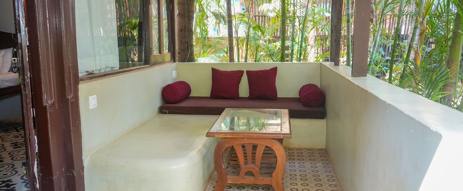 Spacious seating area with cushioned sofas and a wooden table, offering a view of nature at De Soul Santé, Morjim.