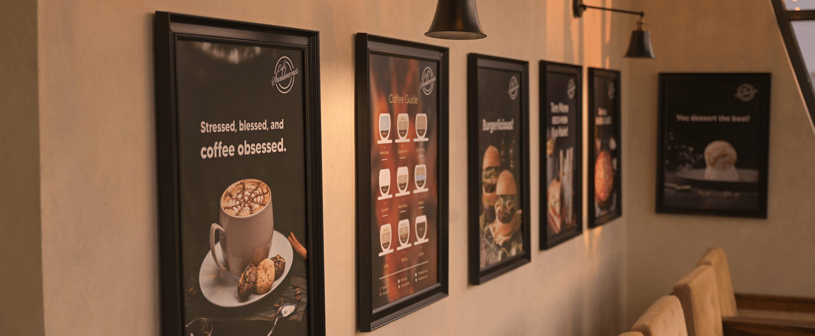 Framed coffee-themed artwork displayed along a softly lit wall inside the cafe at Hotel Sonar Bangla Mayapur.