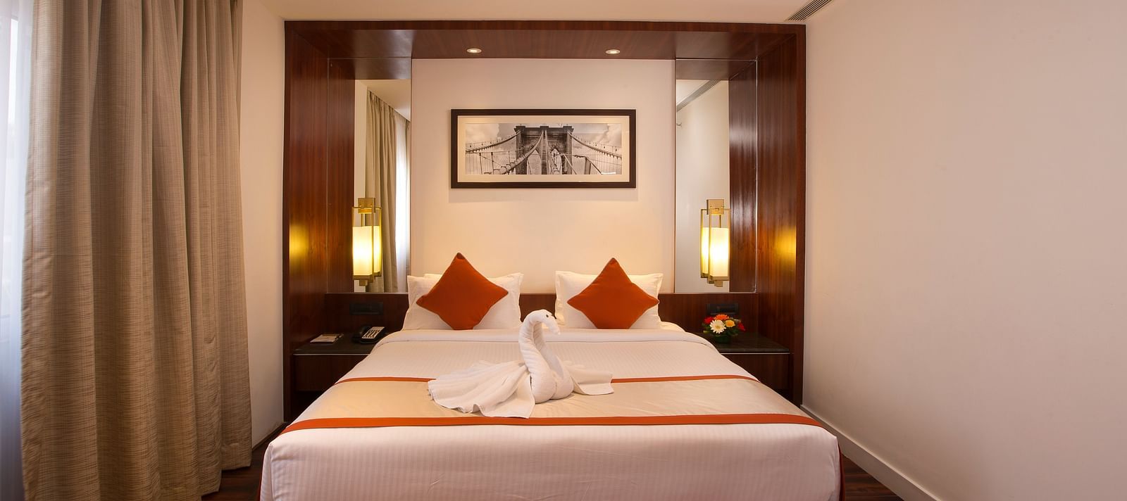 A hotel room featuring a large bed with white linens and red accents, a desk and a wall-mounted TV - Hotel Southend by TGI - Bommasandra, Bangalore