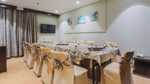 A cosy and well-decorated banquet-style setup with neatly arranged chairs, tables, and vibrant wall art, ideal for intimate gatherings or small meetings.