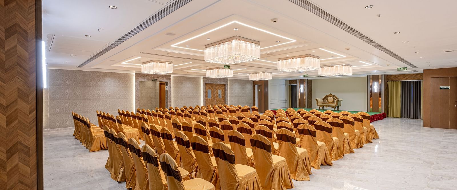 Grand conference hall set up with gold chair covers and chandeliers at Lemonridge Hotels, IDPL Balanagar.