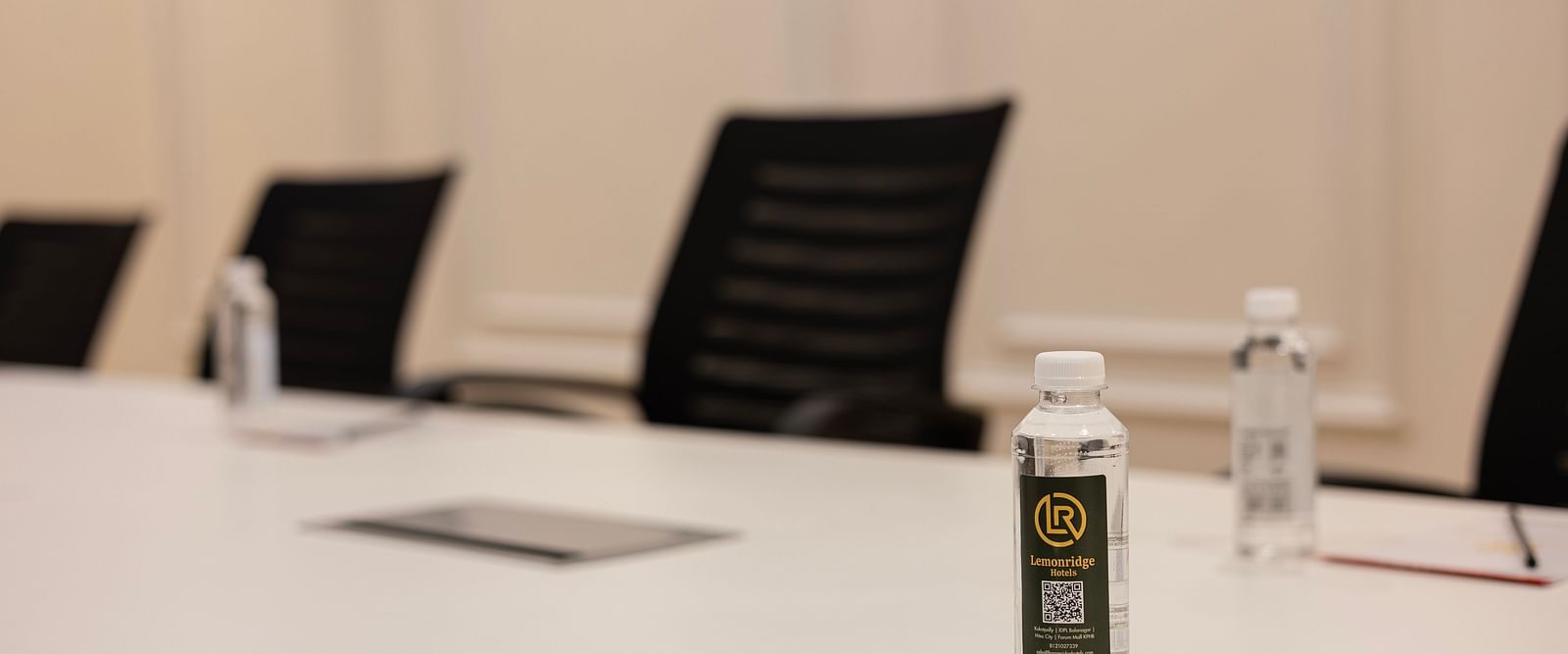 Close-up of boardroom table with bottled water and notepads at Lemonridge Hotels, IDPL Balanagar.