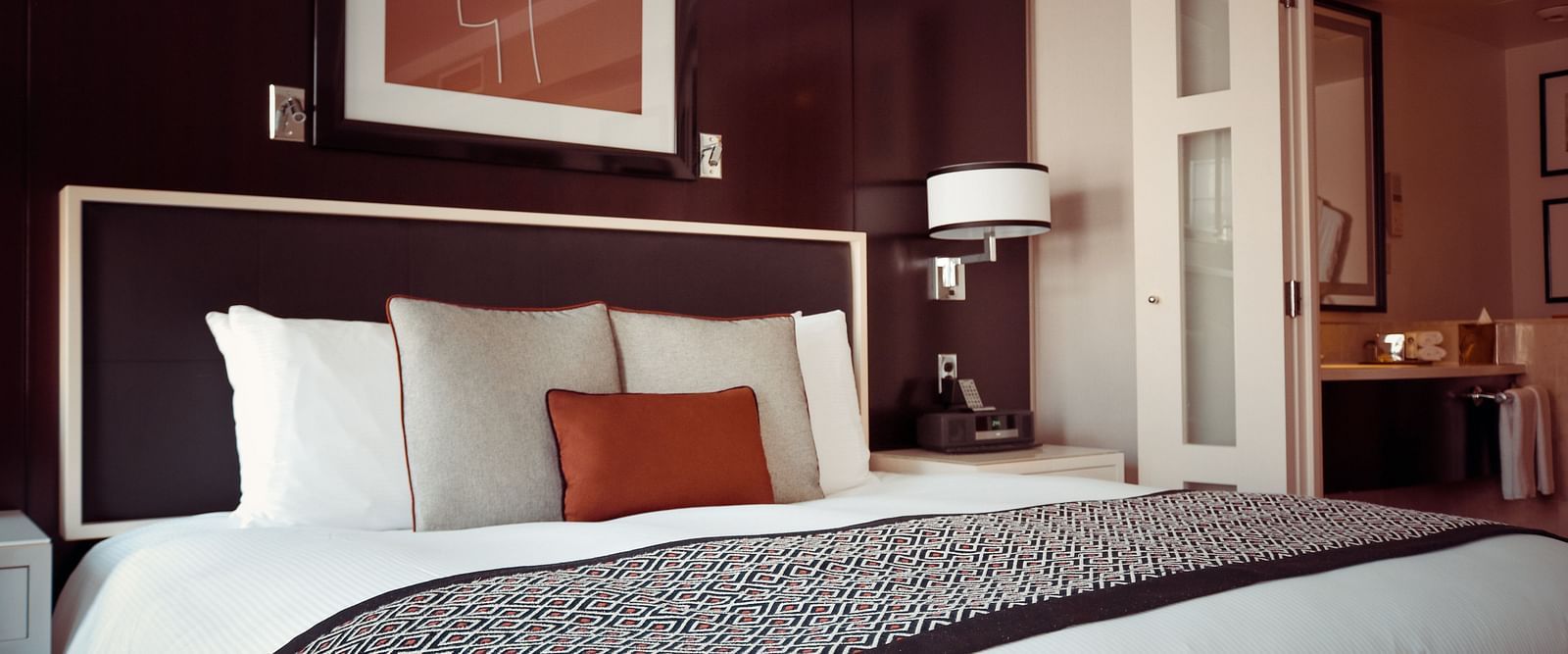 a hotel bedroom with a large bed with pillows and a side lamp