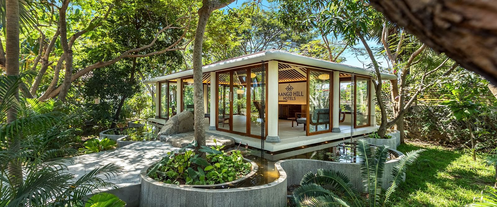 Modern glass-walled building surrounded by lush greenery | Mango Hill Shallow Beach Resort ECR