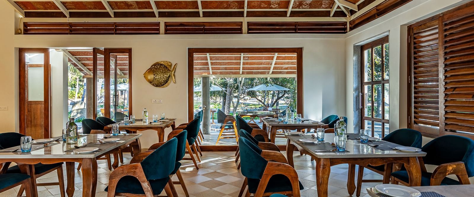 Image of a restaurant by the beach with wooden interiors blue chairs, and a high, patterned ceiling | Mango Hill Shallow Beach Resort ECR