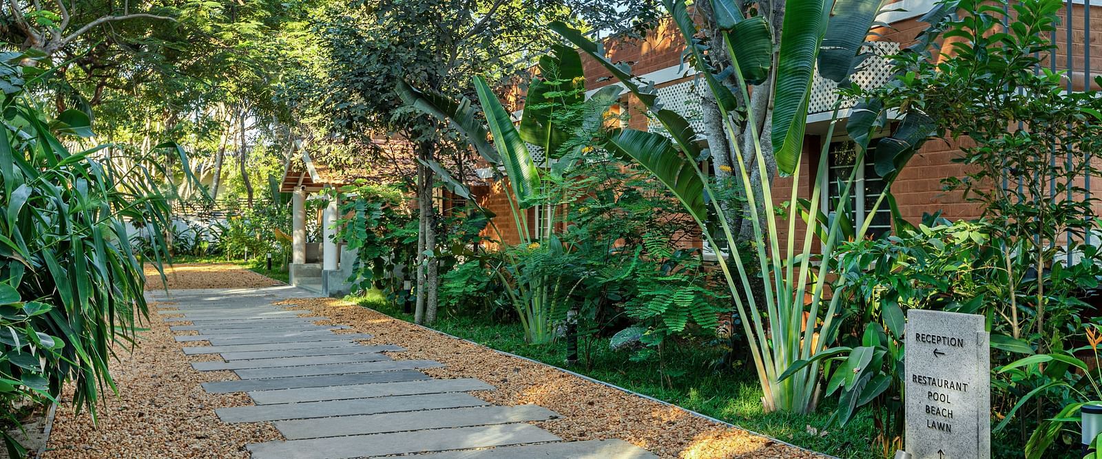 Path leading through lush greenery at a tropical resort | Mango Hill Shallow Beach Resort ECR