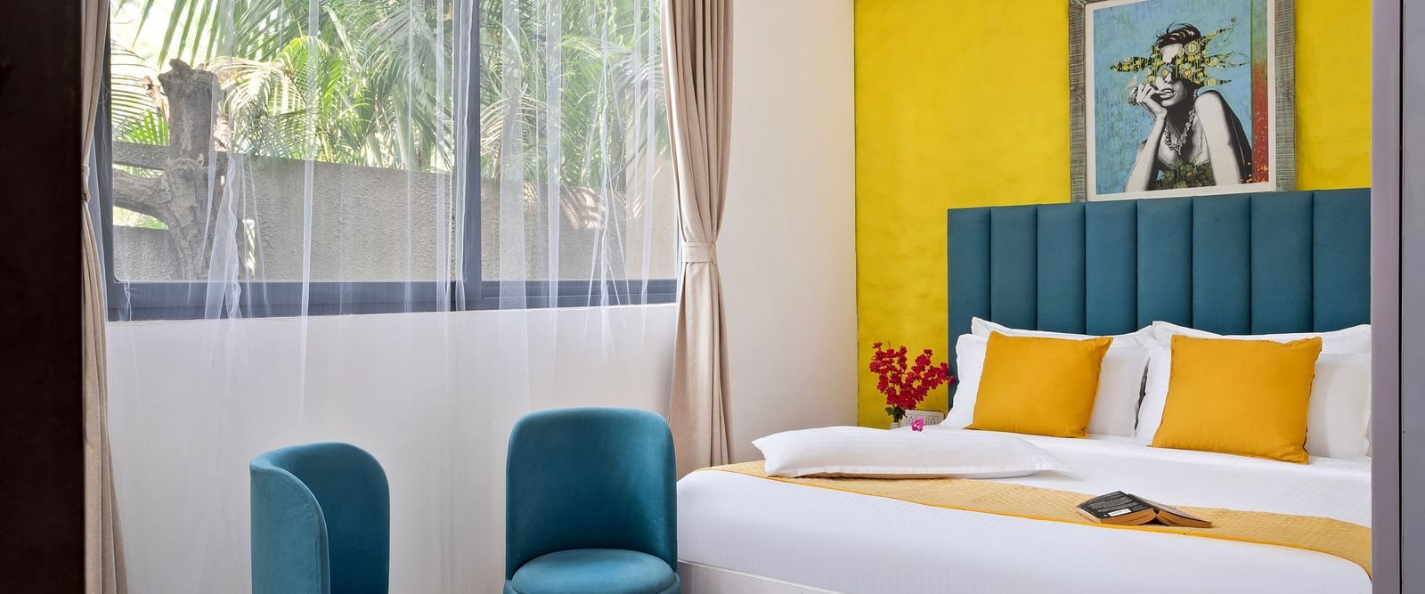 Bedroom featuring artistic decor, bold colours, and a serene outdoor view.