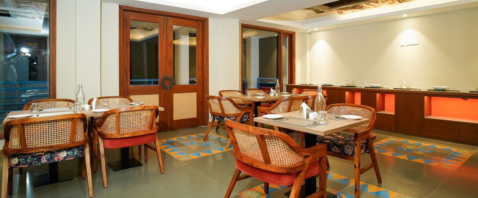 A dining area with multiple tables and chairs, featuring wooden accents and a patterned ceiling | Sukama Resort & Spa, Nainital
