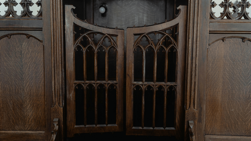 Close-up of dark wooden swinging doors with arched lattice carvings, set within a larger wooden frame.