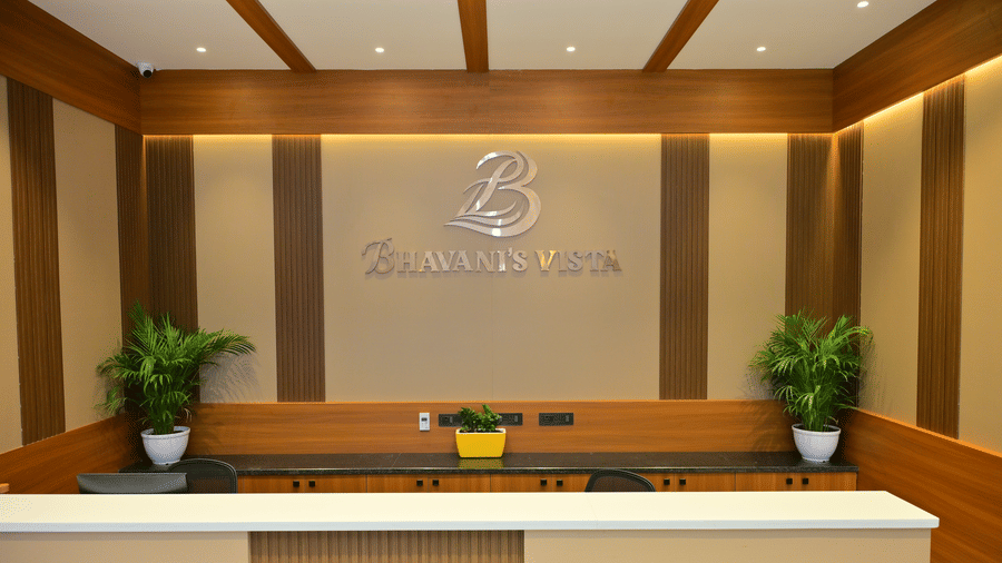 Reception desk of Bhavanis Vista By Icon featuring a counter, signage, and potted plants.