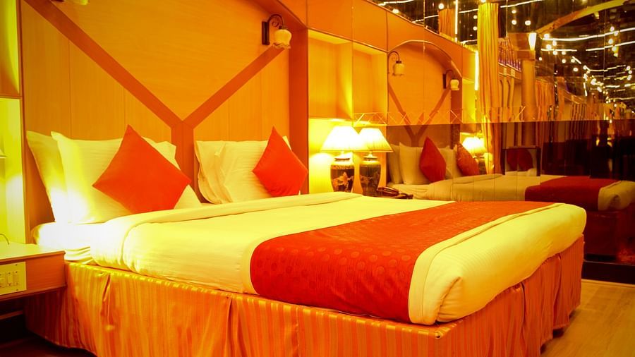  Hotel Yasodha Towers - Interior view of a bedroom with brown coloured interiors, a queen size bed and lamps on either sides