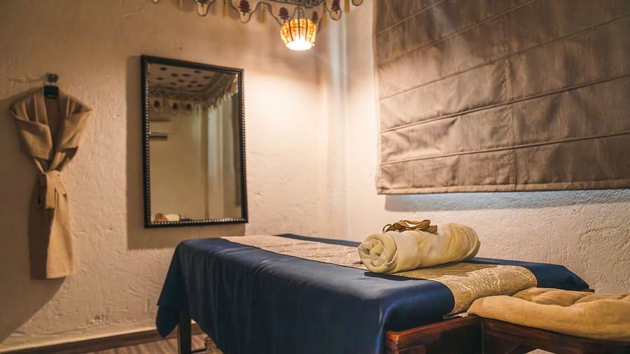Spa table with a folded towel on top and a spa cloak hanging on the wall near a mirror.