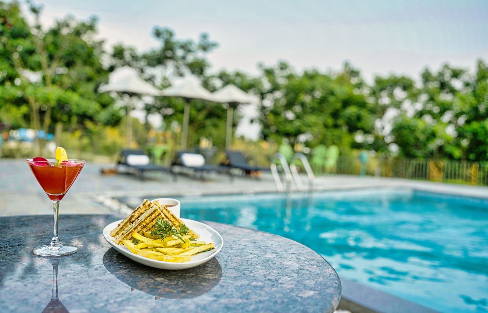A picture with refreshing cocktail by the pool, with a snack platter and a beautiful view Atman, dharamshala