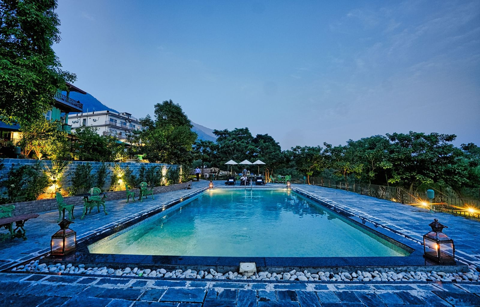 An image featuring swimming pool surrounded by trees, with a beautiful nature view in the background - Atman, dharamshala.