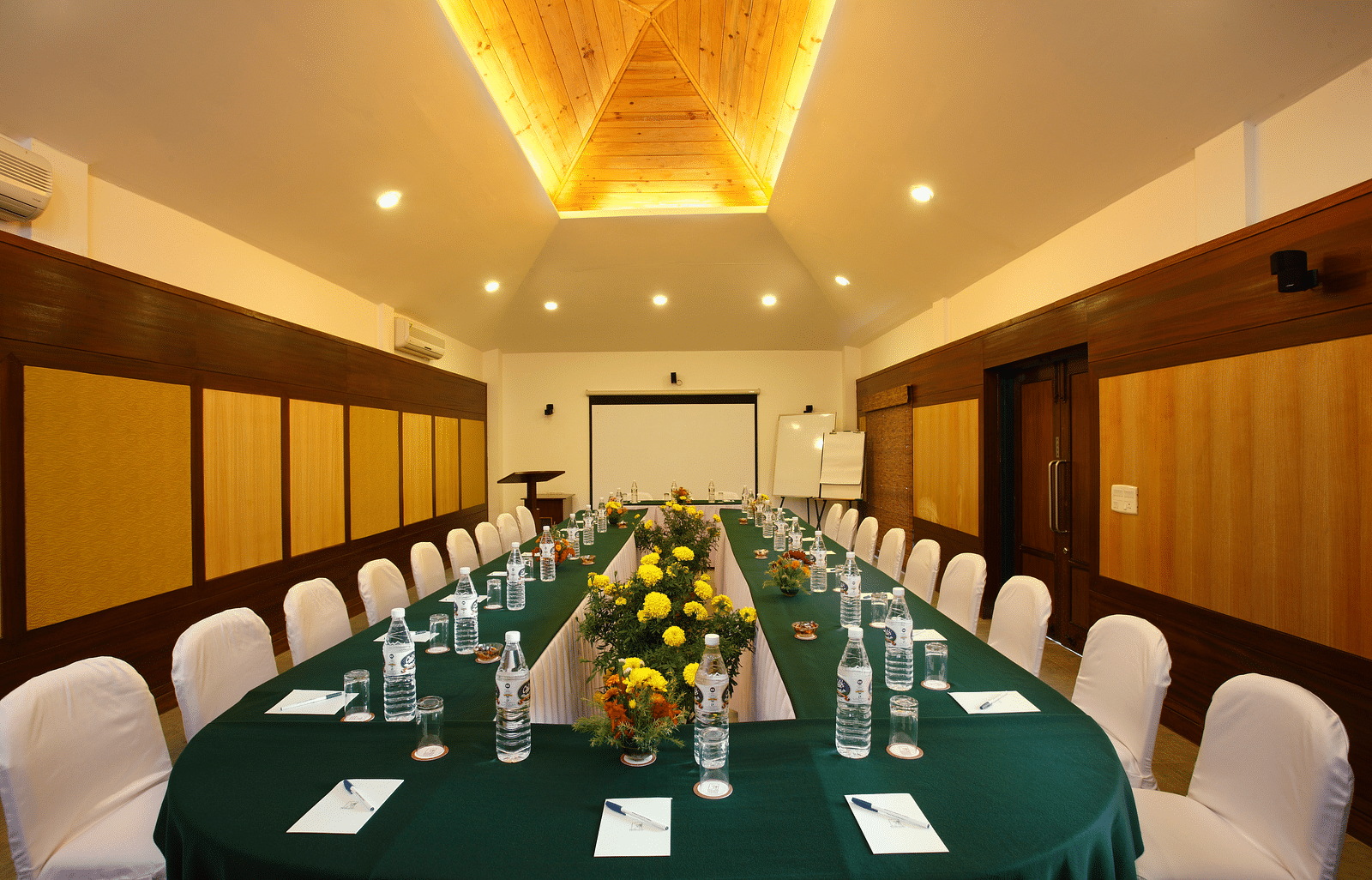 Conference hall with arranged chairs and projector at baikunth Resort, Kasauli 