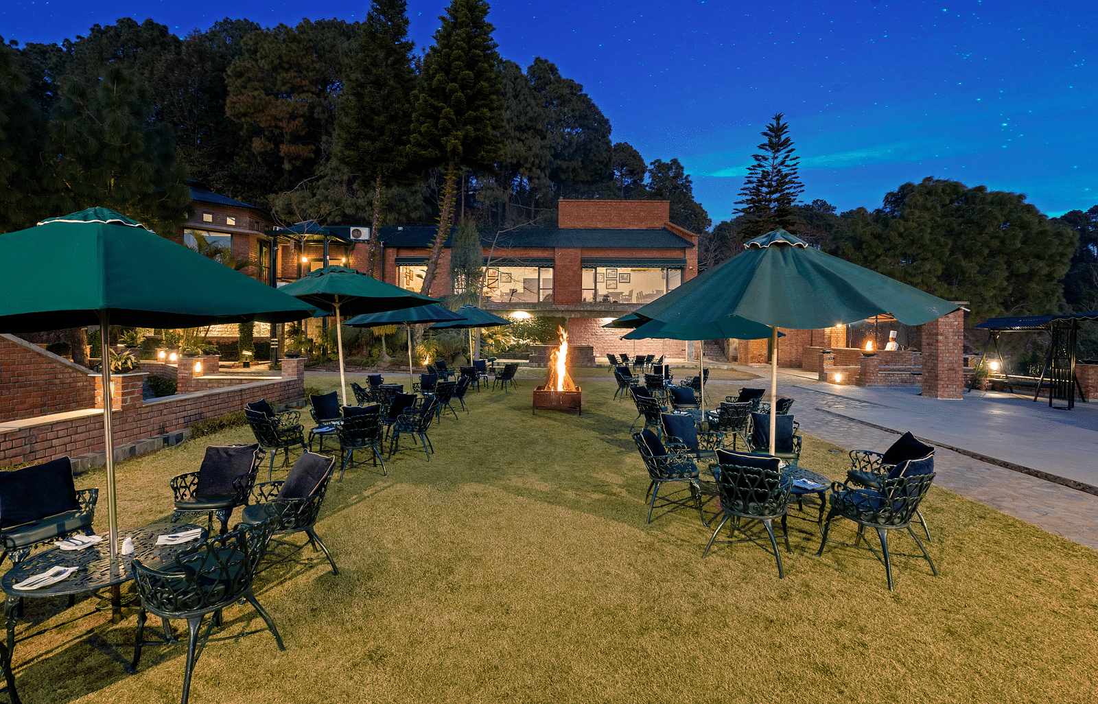 Outdoor Bonfire at Baikunth resort, kasauli with arranged chairs under the umberalla. 