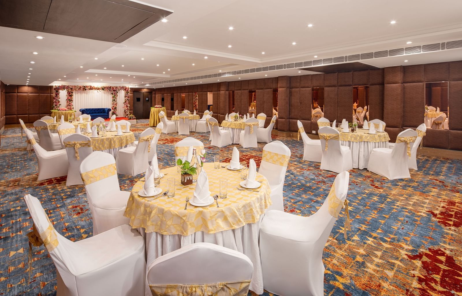 An image of a banquet hall with several chairs and table sets spread out - Brij Eternity, Vrindavan