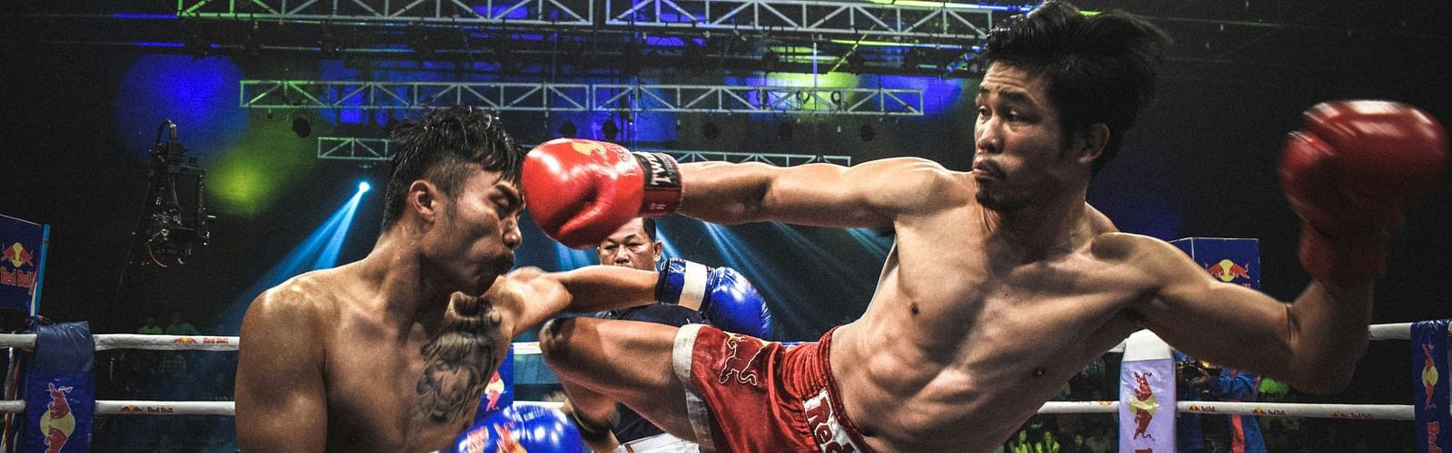 two muay thai fighters fighting inside a ring with a referee behind them officiating