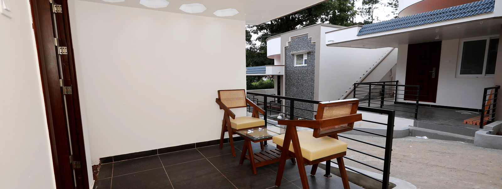 The entrance of the Terrace Cottage with an outdoor seating area featuring 2 arm chairs at WOW Naturefull Resorts, Yercaud.