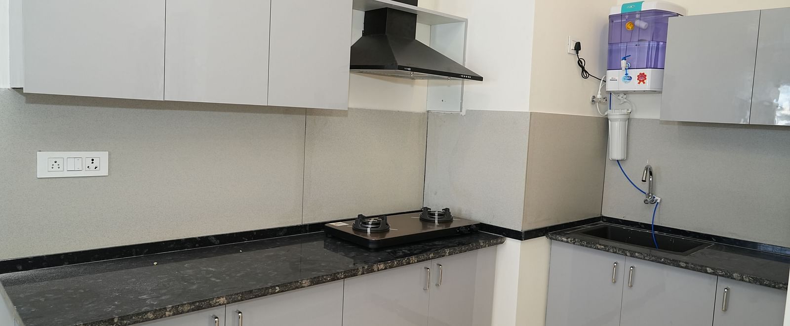 a well equipped kitchen with a chimney and a water purifier - Hotel Grand Sigma