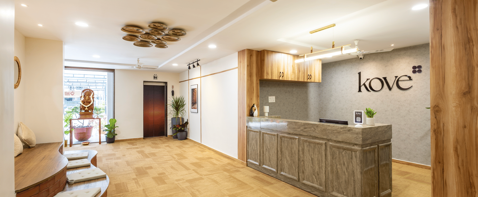 Wide view of Kove Smart Stays' lobby area and reception desk of Kove Smart Stays, showcasing the wooden flooring, ample overhead lighting & seating accommodations.