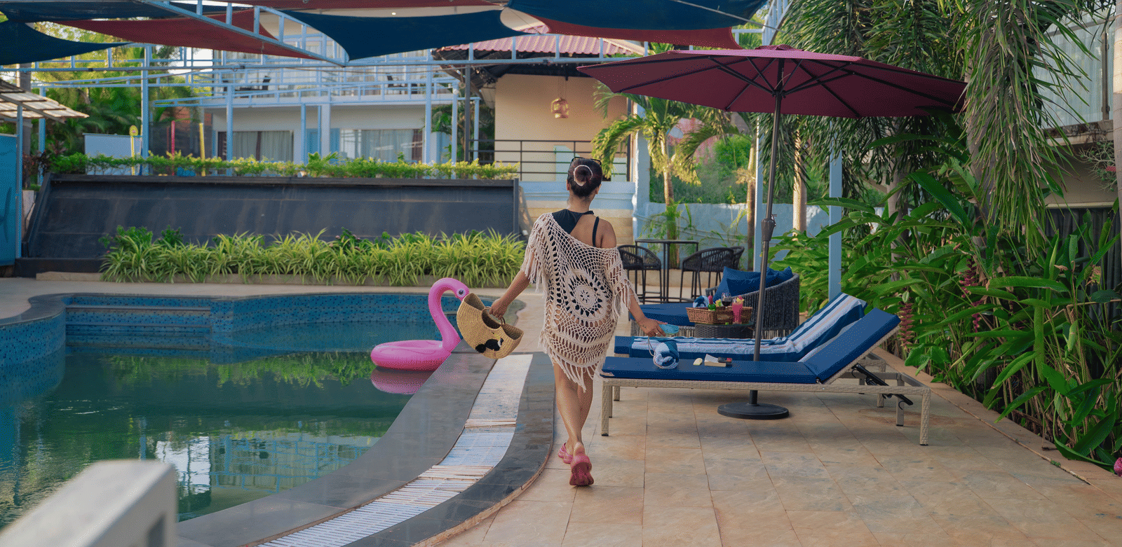 A woman in her poolside outfit walking toward sun loungers placed by the swimming pool - Perfectstayz Koko Maya