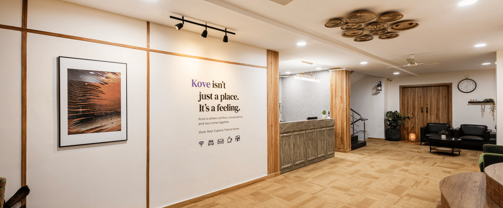 Lobby, entryway, and reception desk of Kove Smart Stays featuring wooden interiors, ample lighting, & signage of a quote on the wall.