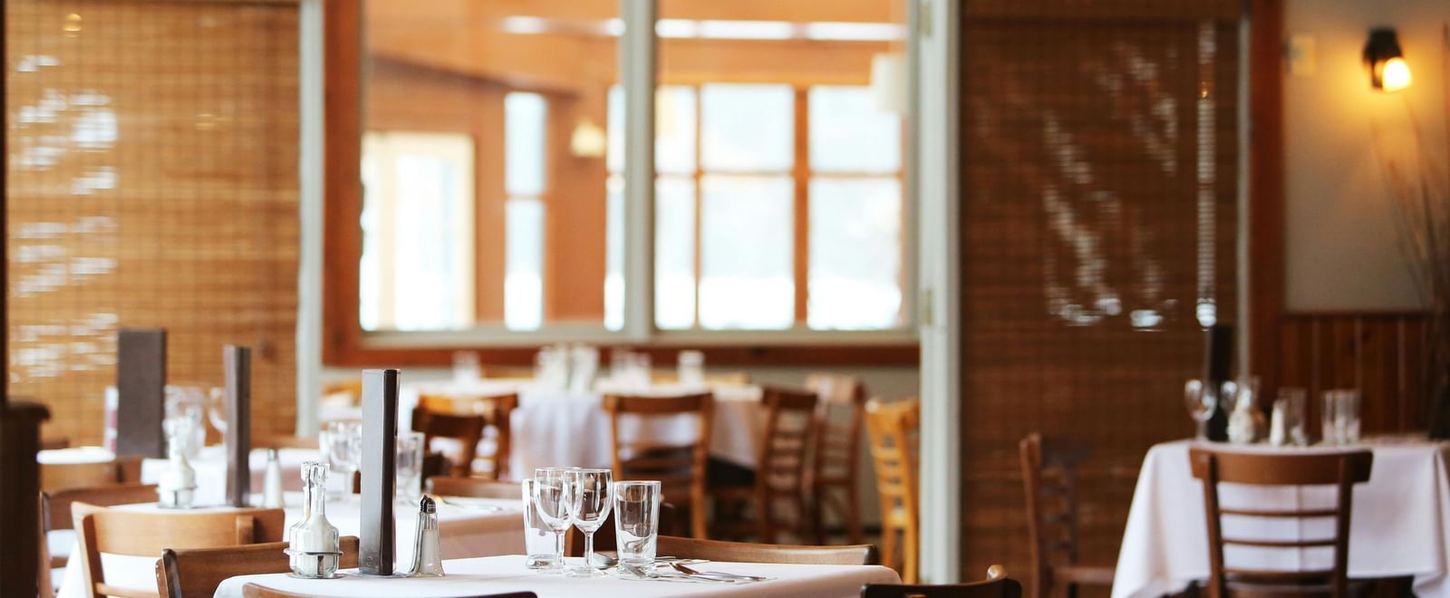 A restaurant interior with tables set with white tablecloths and chairs.