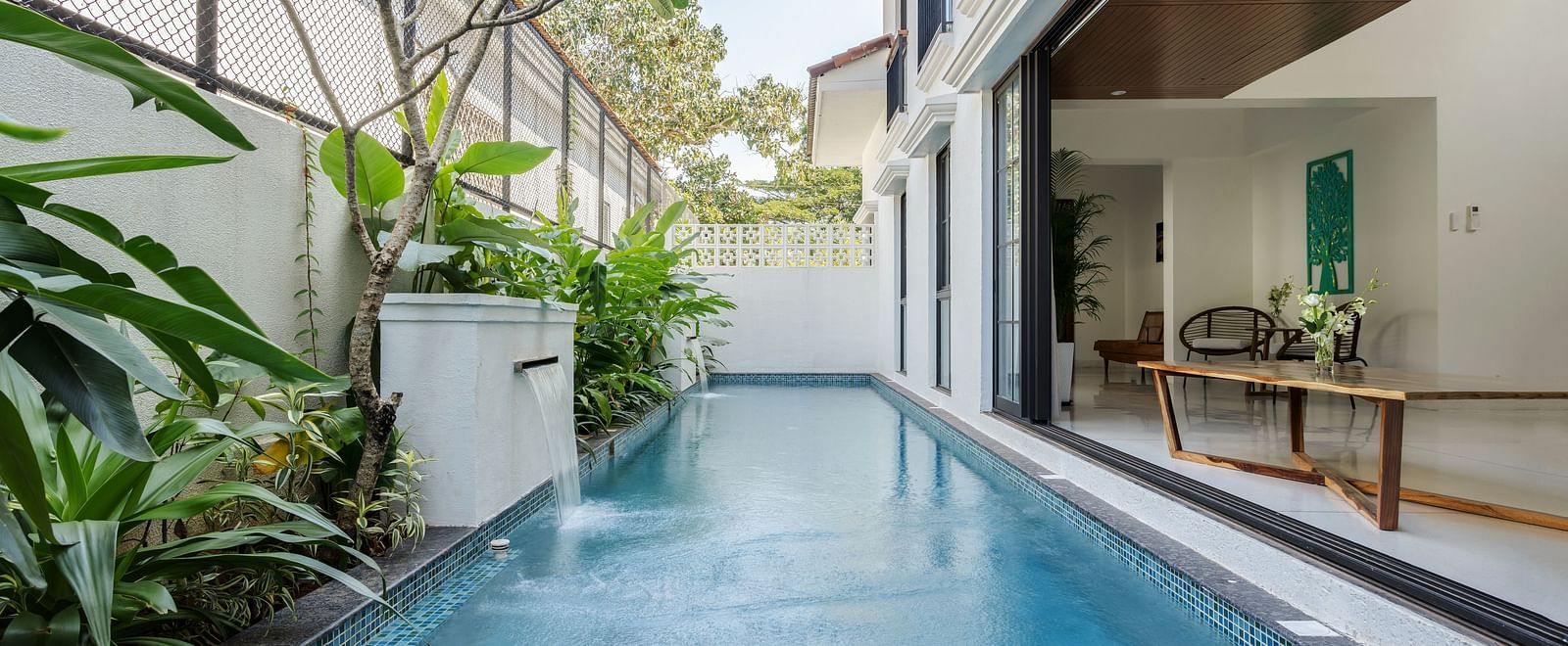 A tranquil outdoor pool surrounded by lush greenery, with modern villa walls and a relaxing atmosphere - BluSalzz Villas - Alocassia, Anjuna