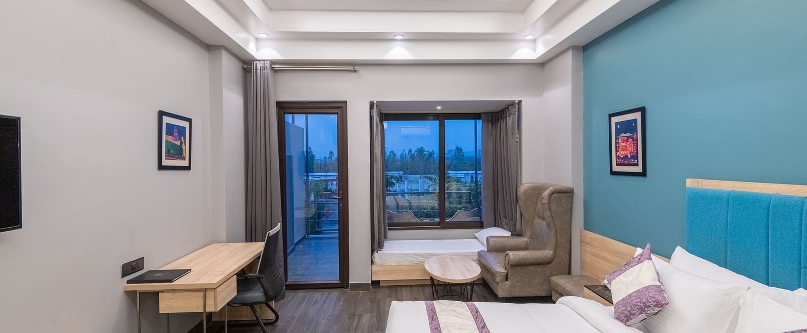 Guest room with cosy bed, reading lights and seating area near balcony - DLS Forest Vines Resort & Spa, Ramnagar (Jim Corbett)
