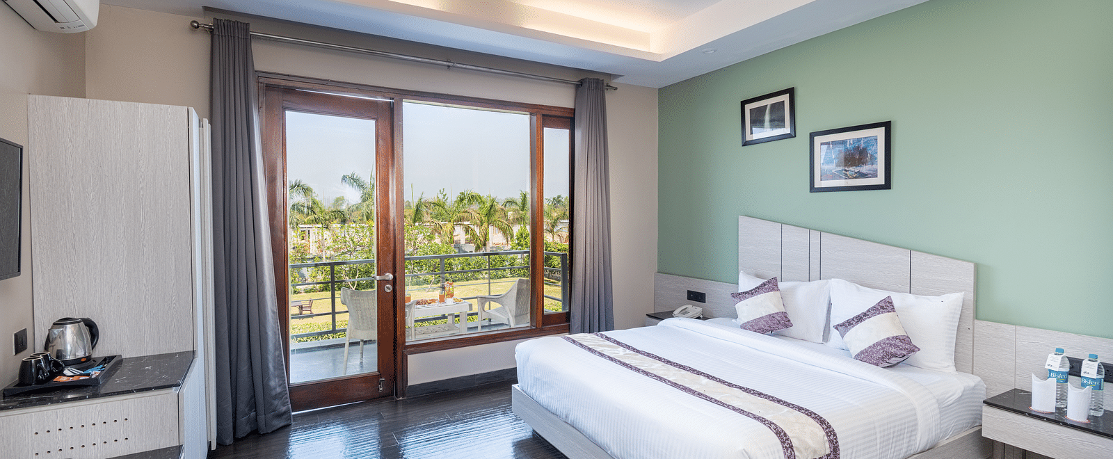 Spacious room at DLS Forest Vines Resort featuring a large bed, a bedside table, and a large glass door leading to the balcony.