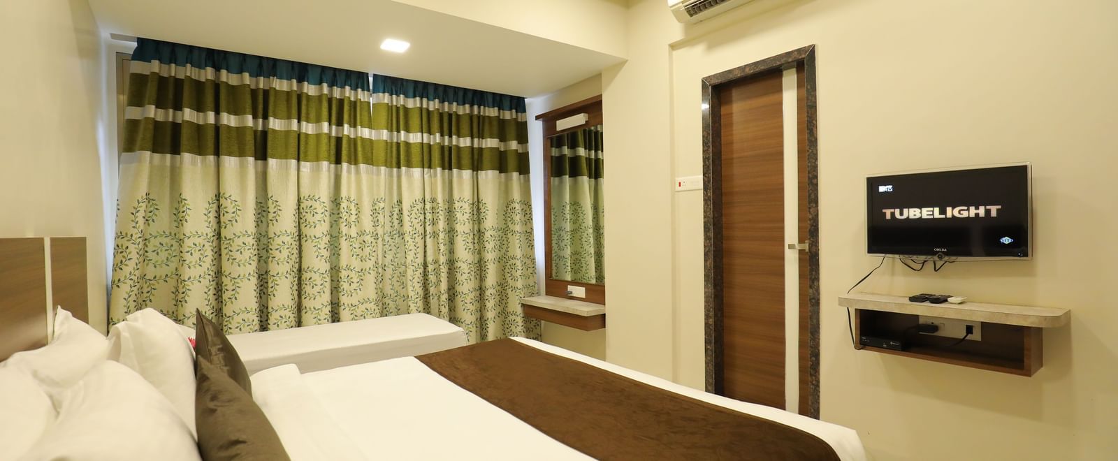 The queen size bed in the Deluxe Room of Highland Resort facing the wall-mounted TV.