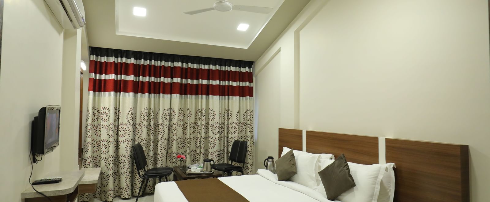 The Deluxe Room at Highland Resort features a queen size bed, a seating area for two, air-conditioning, and a wall-mounted TV.