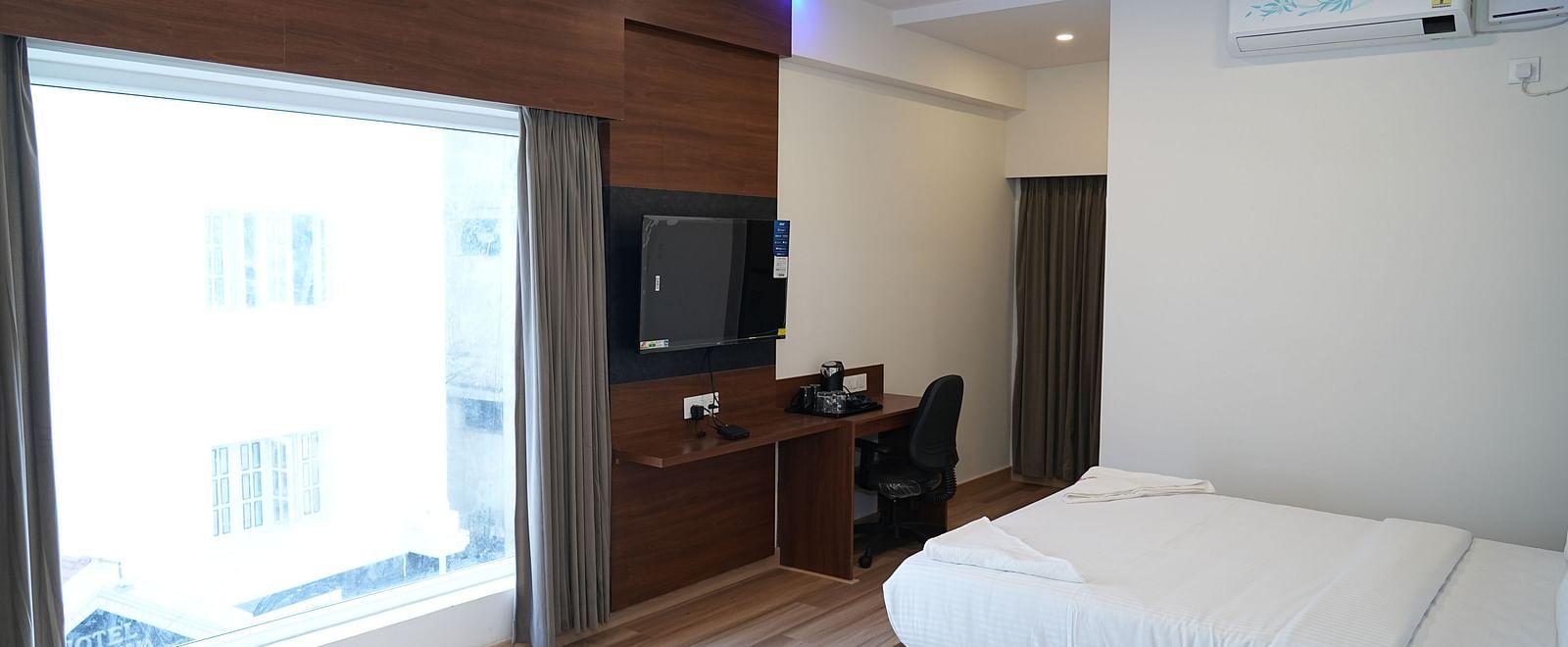 a huge window allowing plenty of natural light to enter the room highlighting the double bed and the coffee table beside it - Hotel Grand Sigma