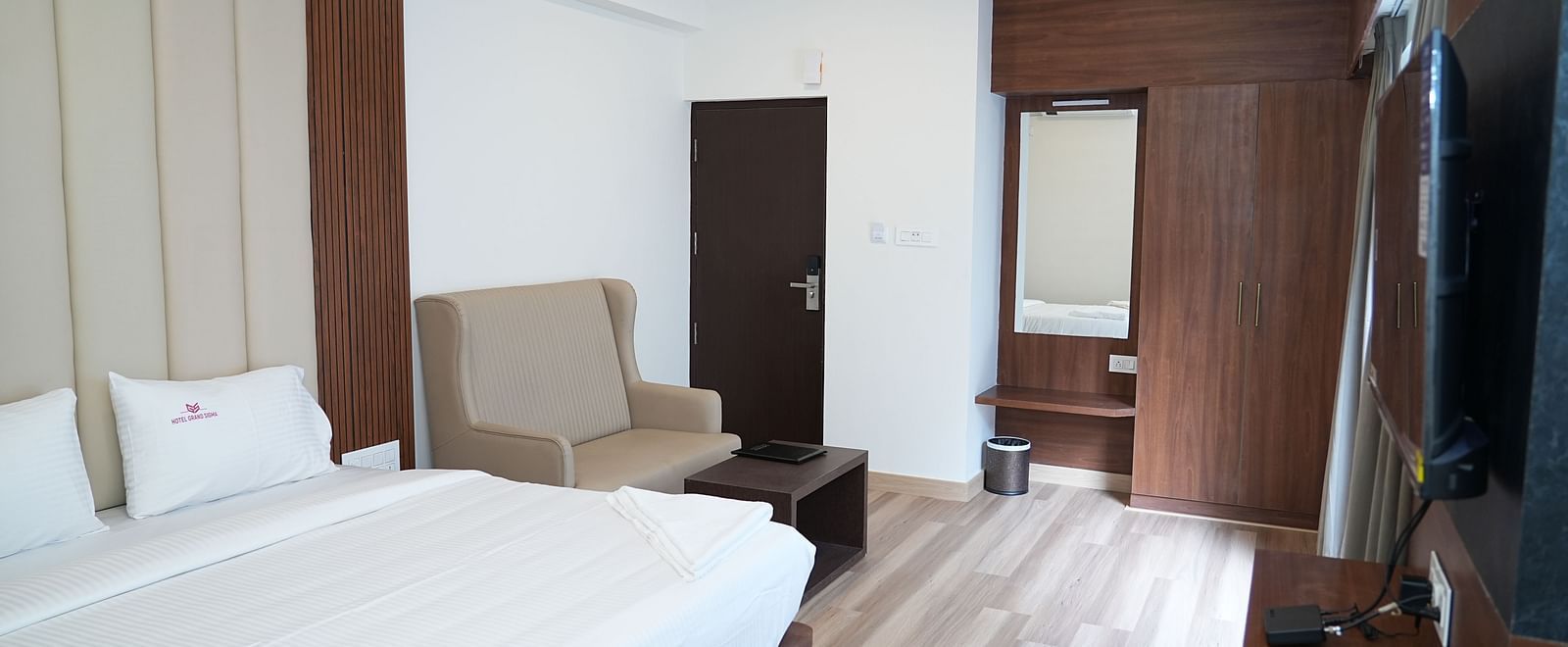 a modern room with rustic interiors featuring a double bed alongside a common seating area and a dressing table in the room - Hotel Grand Sigma