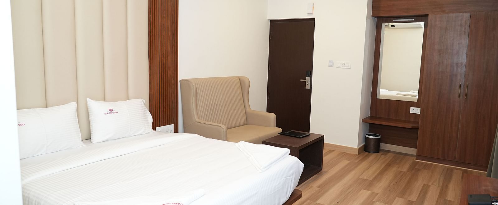 corner view of the room featuring a small dressing table at the far end of the room with wooden flooring - Hotel Grand Sigma