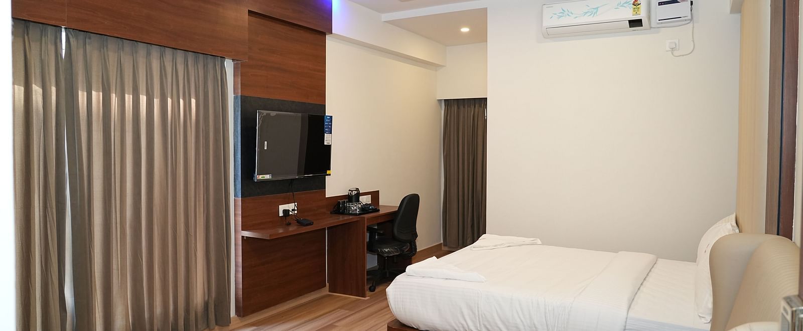 full view image of the premium executive room featuring a double bed in the corner along with  wall mounted television right opposite to it - Hotel Grand Sigma