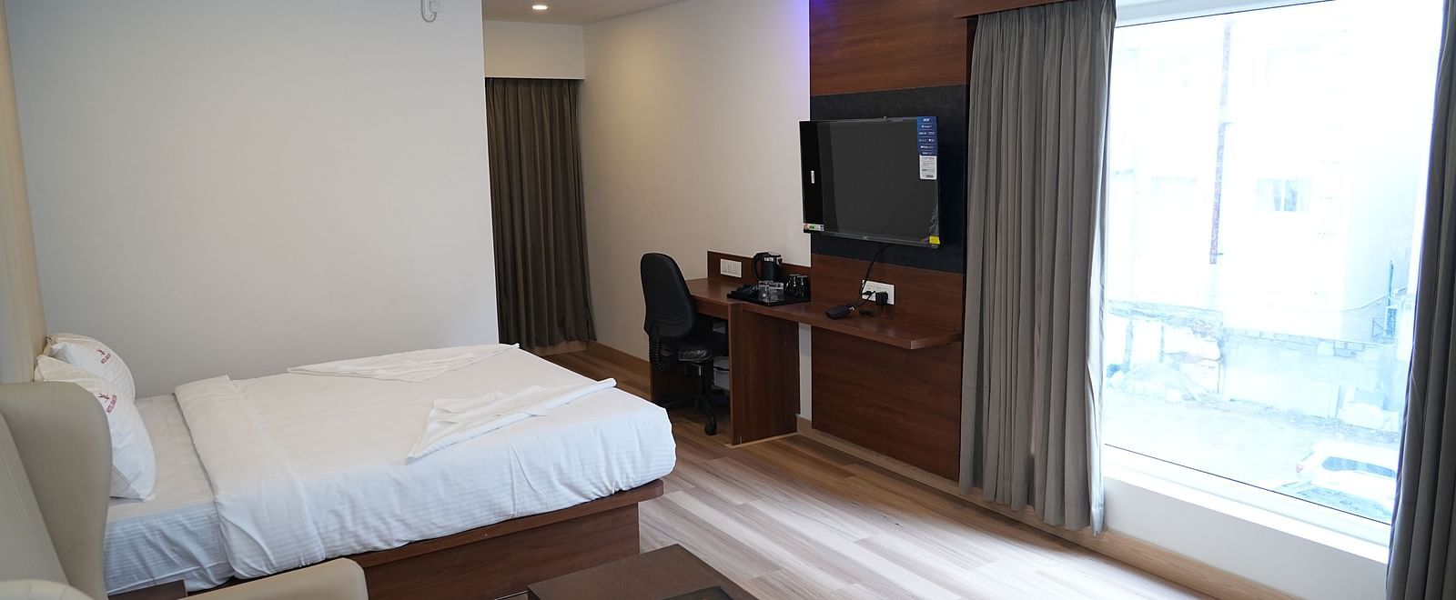 a spacious room featuring a cosy double bed placed right opposite to the huge window allowing ample natural light into the room - Hotel Grand Sigma