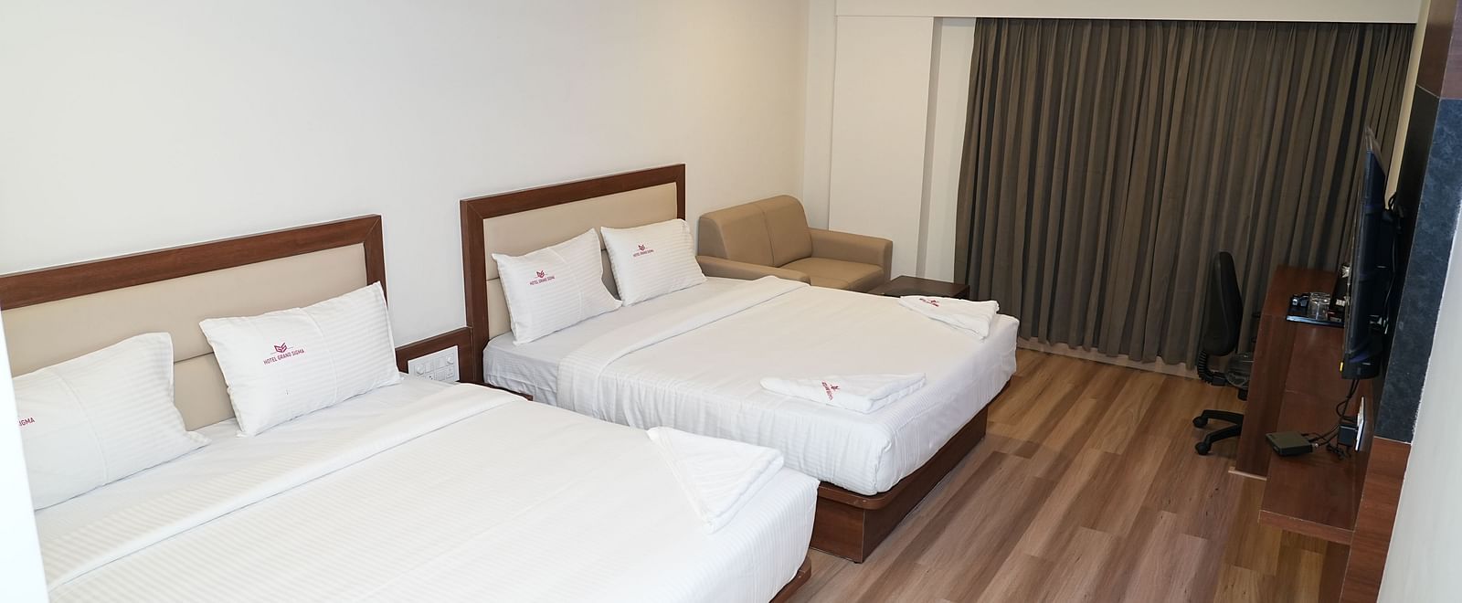 corner view image of the quadruple room with two double beds kept in the room with ceiling fans - Hotel Grand Sigma