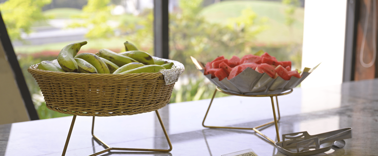 Fresh fruits including bananas and watermelon arranged in baskets on the buffet table at Hotel Sonar Bangla Mayapur.