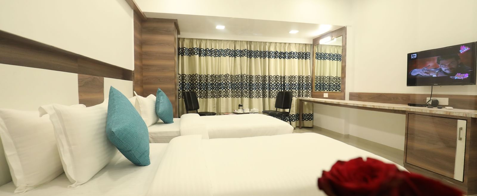 A close-up view of a bed at Imperial Grande with white bedding and a red rose placed near it.
