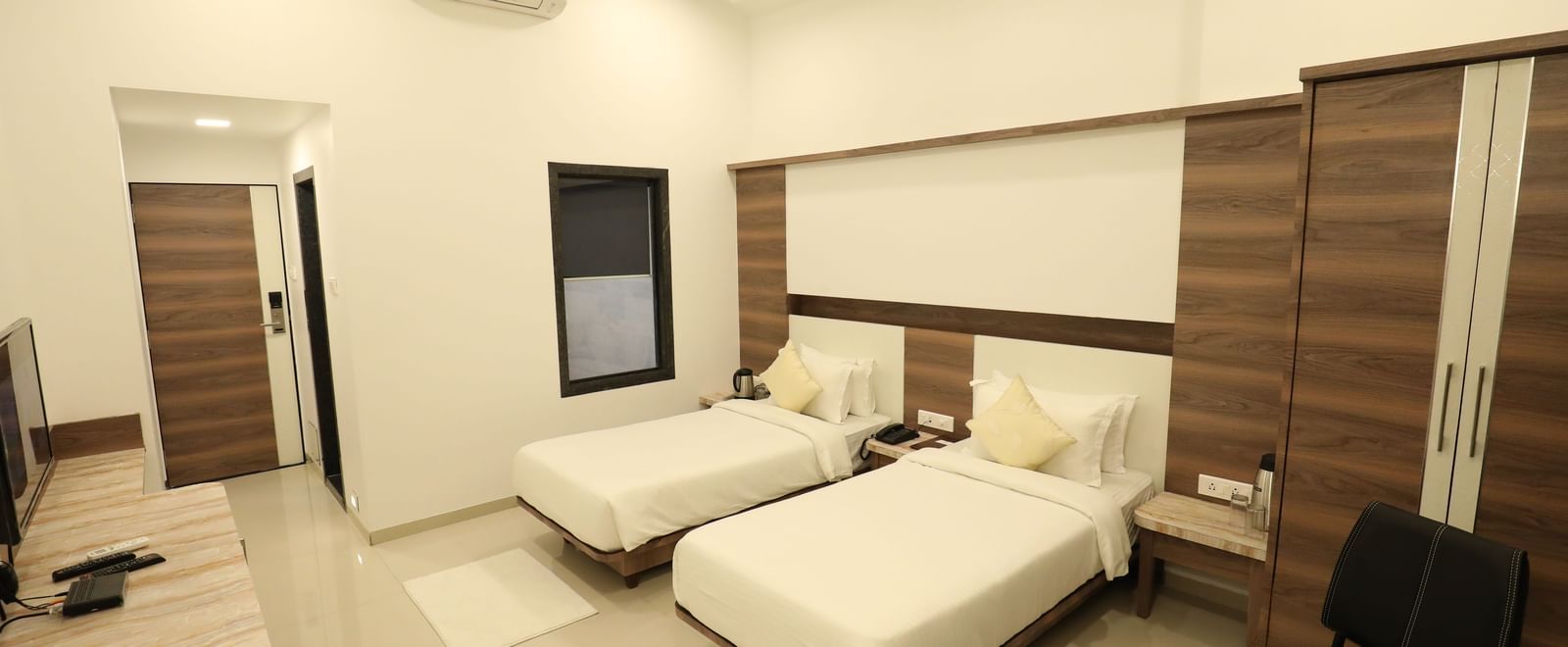 A room in Imperial Grande with twin beds, a television, and wooden accents on the walls.