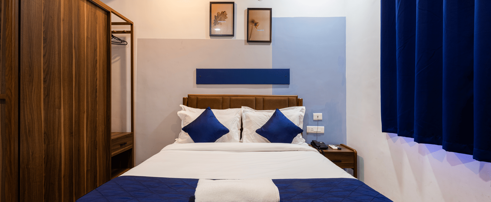 Close up of a tight-knit 4BHK of Kove Smart Stays showcasing the queen size bed located right beside the wooden wardrobe.