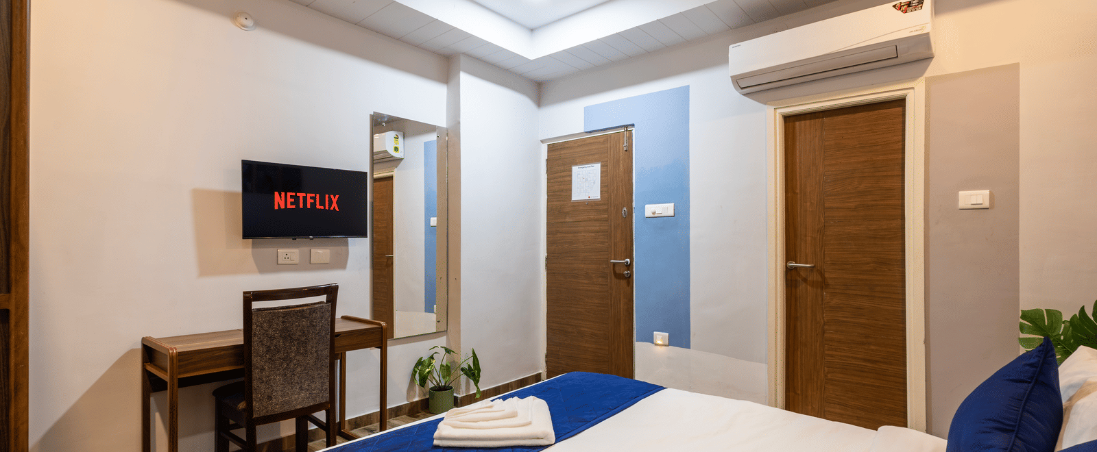 Diagonal view of a bedroom in the 4BHK of Kove Smart Stays, highlighting its plush queen size bed facing the wall-mounted television.