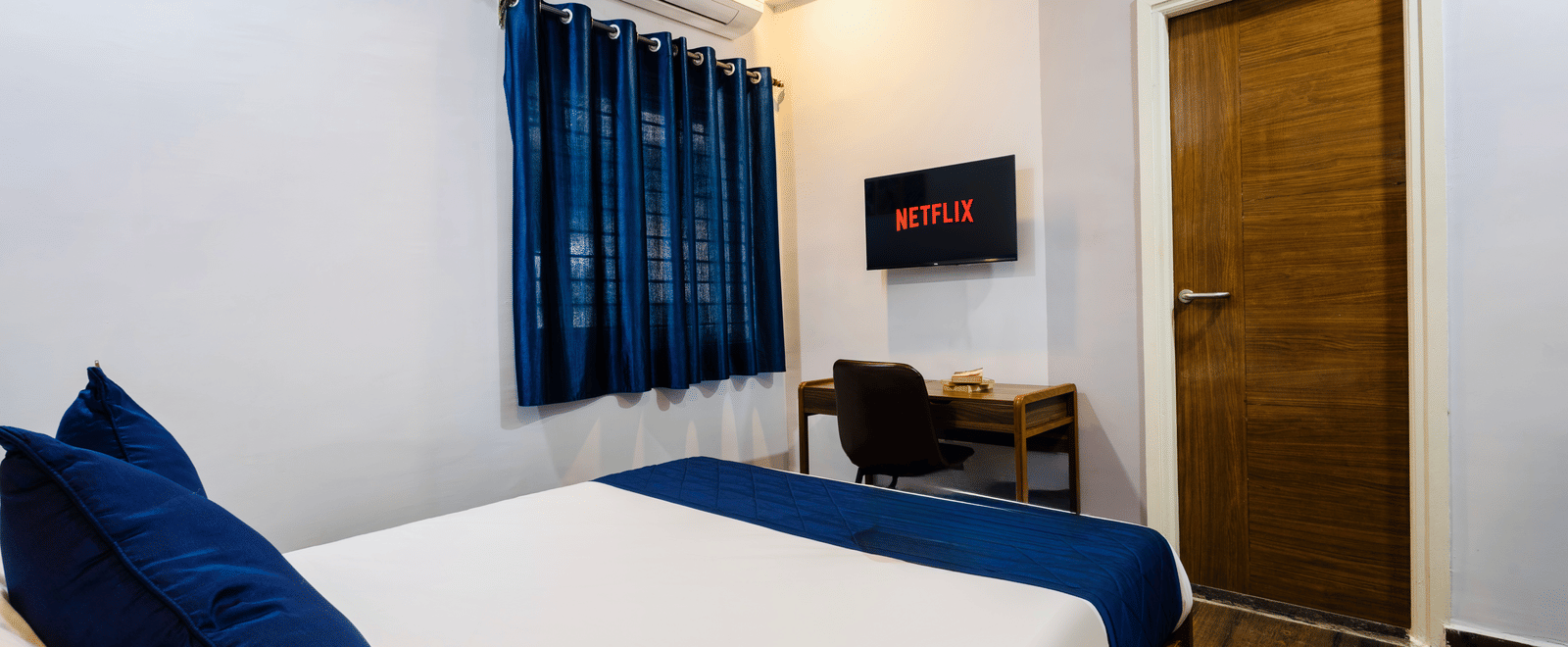 Bedroom of Studio Room featuring the queen size bed facing the wall-mounted TV and work desk.