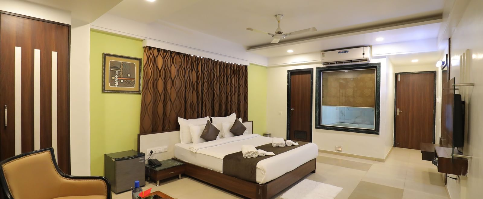 A wide view of a bedroom at Krushnai Resort, with a king size bed, seating area, and wall decor.